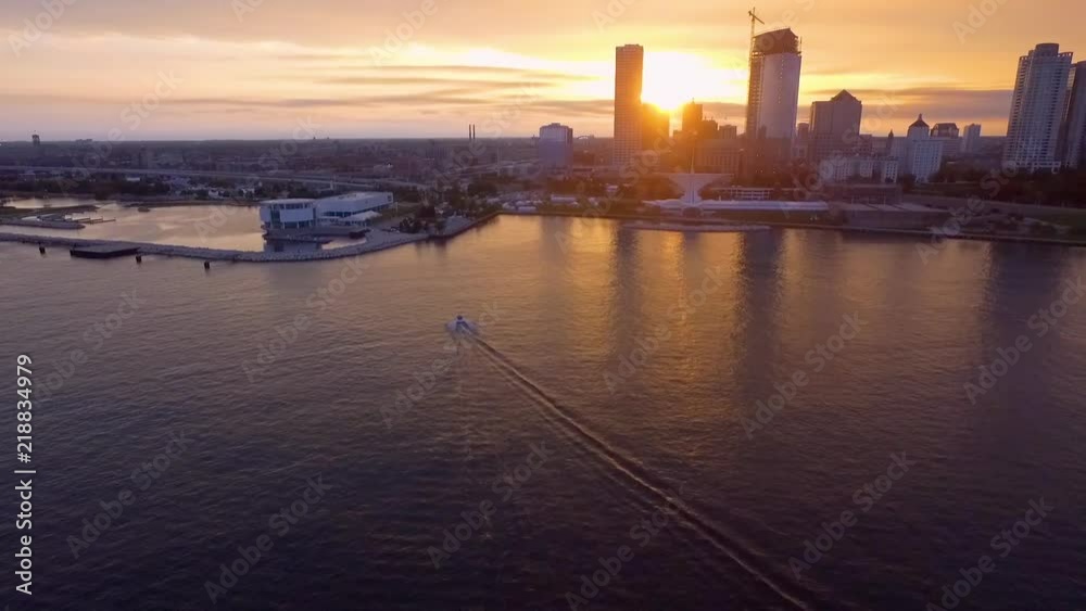 This stunning slow motion aerial drone clip follows a motorboat as it glides through the serene waters of the harbor of Milwaukee Wisconsin at sunset. A perfect establishing shot. This stunning slow motion aerial drone clip follows a motorboat as it glides through the serene waters of the harbor of Milwaukee Wisconsin at sunset. A perfect establishing shot.