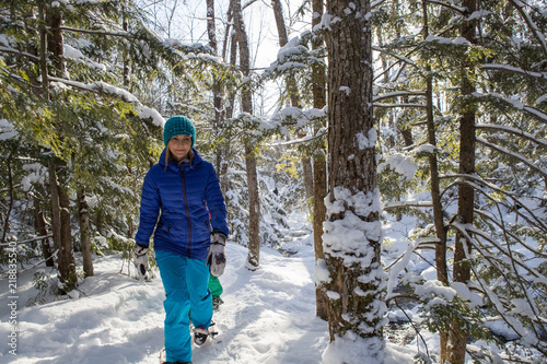 Beautiful woman snowshoeing in the forest.