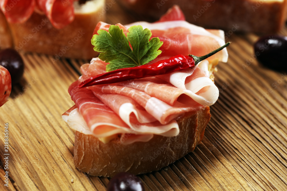 Sandwich with prosciutto or salami or crudo. Antipasti gourmet bruschetta snack.