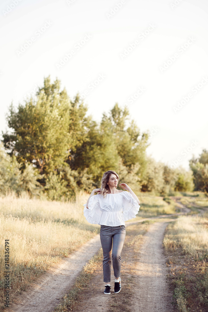 Young woman standing on a wheat field with sunrise on the background