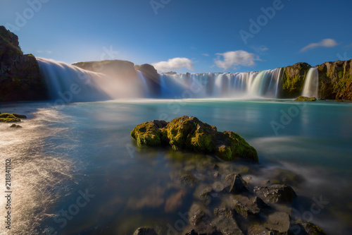 Iceland s Godafoss waterfall on a clear  sunny day.  The falls creating streams of light through the water 