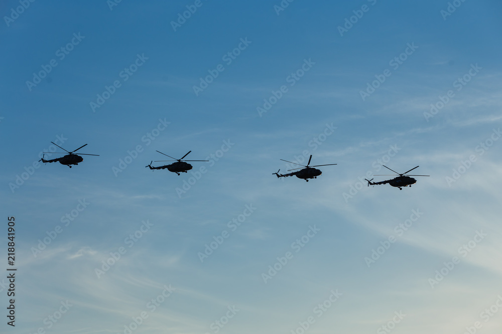 Flight of four military helicopters. Air parade. Air force day. Side view. Flight formation. Serene blue sky and white clouds. Flight of four military helicopters. Air parade. Air force day. Side view. Flight formation. Serene blue sky and white clouds.