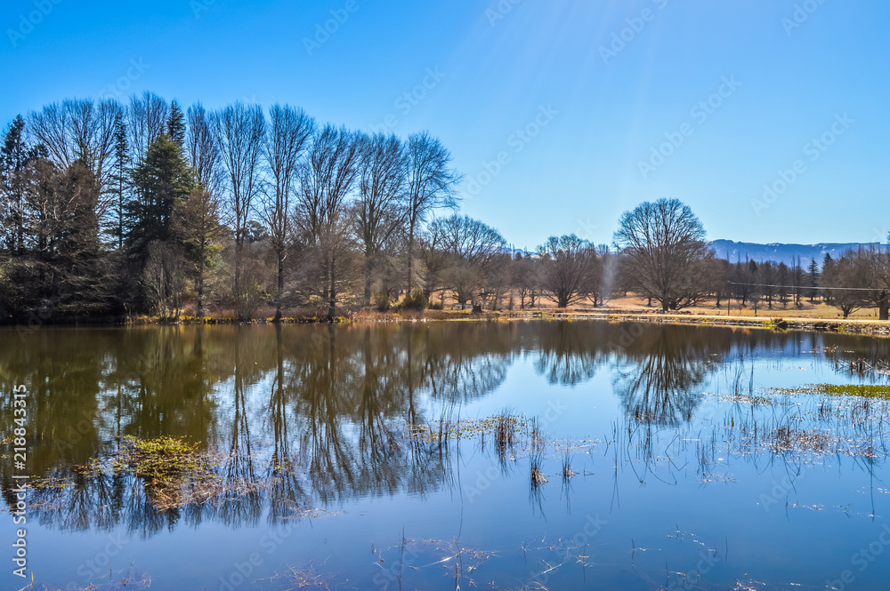 A picturesque and beautiful blue and blue with sun leaks and reflection landscape of Kenmo lake in Underberg South Africa