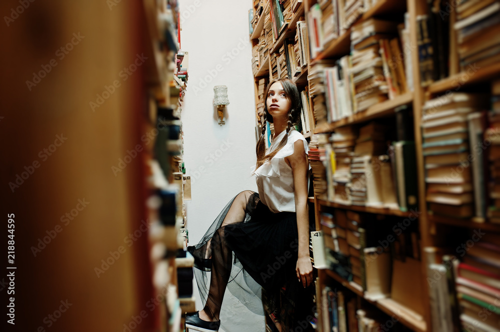Girl with pigtails in white blouse at old library.