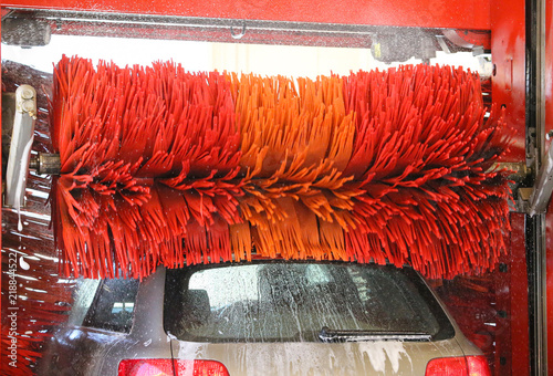 Car wash automatic, red rotating brushes, water spray. Water drops on glass