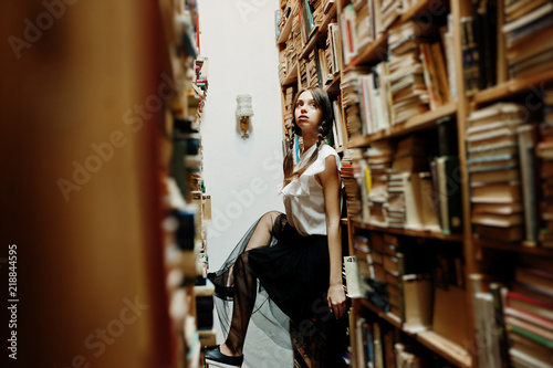 Girl with pigtails in white blouse at old library.