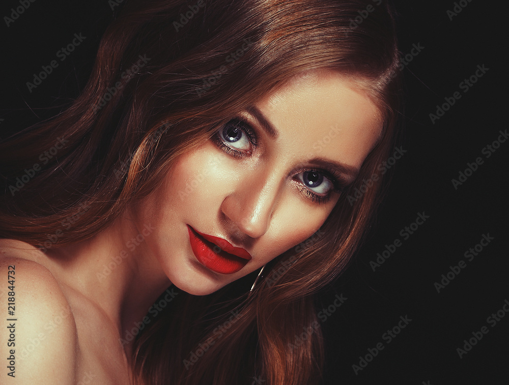 Fototapeta premium Blonde fashion girl with long and shiny curly hair. Red lips and bright make up. Over black background.