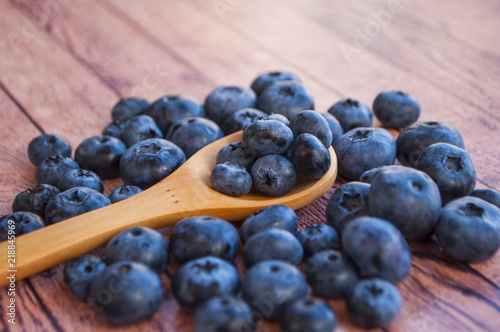 Freshly picked blueberries in a wooden spoon on wooden table. Healthy food concept.