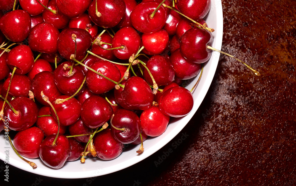 Pile of fresh cherries in the white bowl on the table top angle background Pile of fresh cherries in the white bowl on the table top angle background