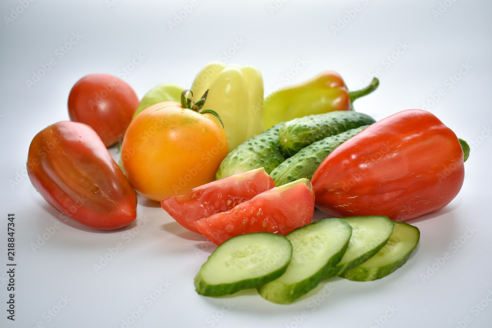 green cucumbers, red bell peppers and tomatoes on a white background, vegetable assortment green cucumbers, red bell peppers and tomatoes on a white background, vegetable assortment