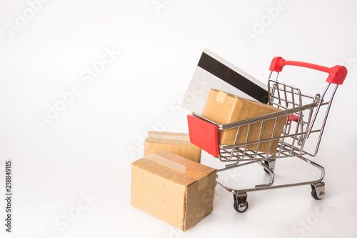 Shopping concept : Cartons or Paper boxes and credit card in red shopping cart on white background. online shopping consumers can shop from home and delivery service. with copy space