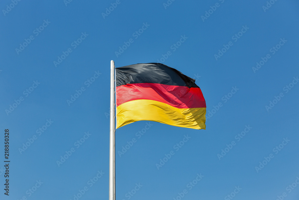 German flag on the flagstaff waving against clear blue sky German flag on the flagstaff waving against clear blue sky