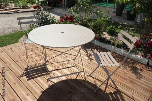 round table and two metal chairs on a wooden deck outside