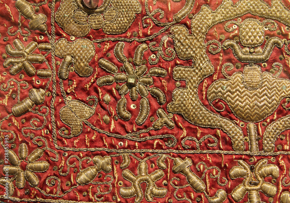 Fototapeta premium Vintage hand embroidery - golden floral pattern on red background
