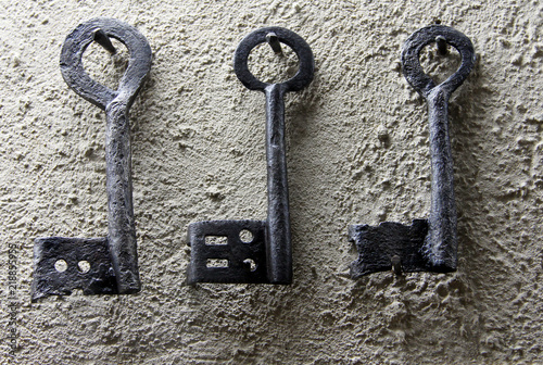 Three vintage black keys on white wall © katoosha