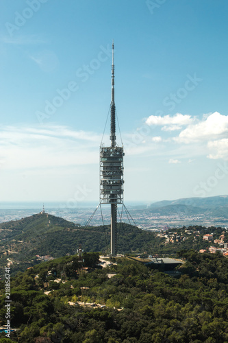 Aerial (panoramic or cityscape) view of the green forest hills of Barcelona (Catalonia, Spain) and TV tower Torre de Collserola from the highest point of Tibidabo Torre de Collserola