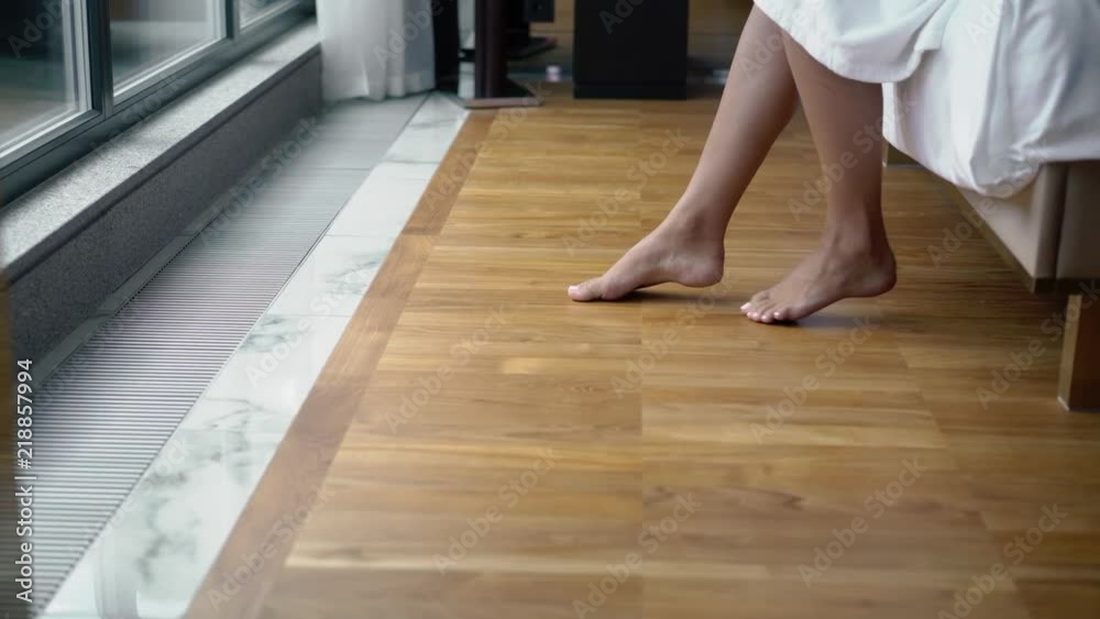 Young woman in bathrobe sitting on a bed in bedroom barefoot in hotel steadicam Young woman in bathrobe sitting on a bed in bedroom barefoot in hotel steadicam
