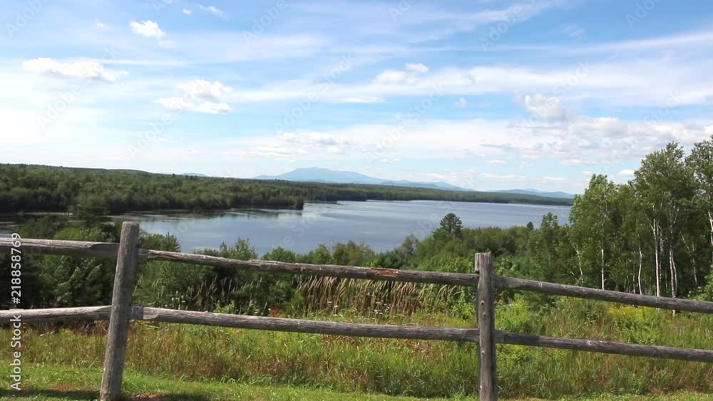 Looking out over a lake under blue skies from behind a rural wooden fence. Looking out over a lake under blue skies from behind a rural wooden fence.