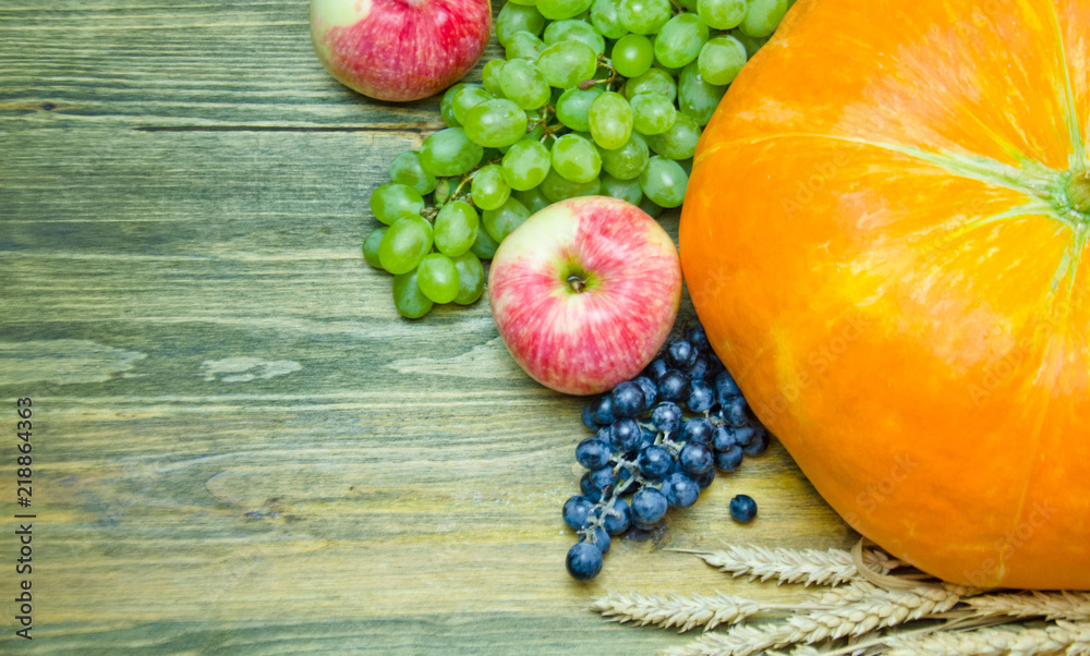 pumpkin and apples and grape brush green and blue and ears on wooden background pumpkin and apples and grape brush green and blue and ears on wooden background