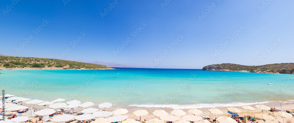 Beautiful colorful beach at Crete island, Greece. Voulisma paradise beach with umbrella and sunbeds.  Summer vacation travel holiday background concept.