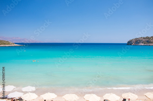 Beautiful colorful beach at Crete island  Greece. Voulisma paradise beach with umbrella and sunbeds.  Summer vacation travel holiday background concept.