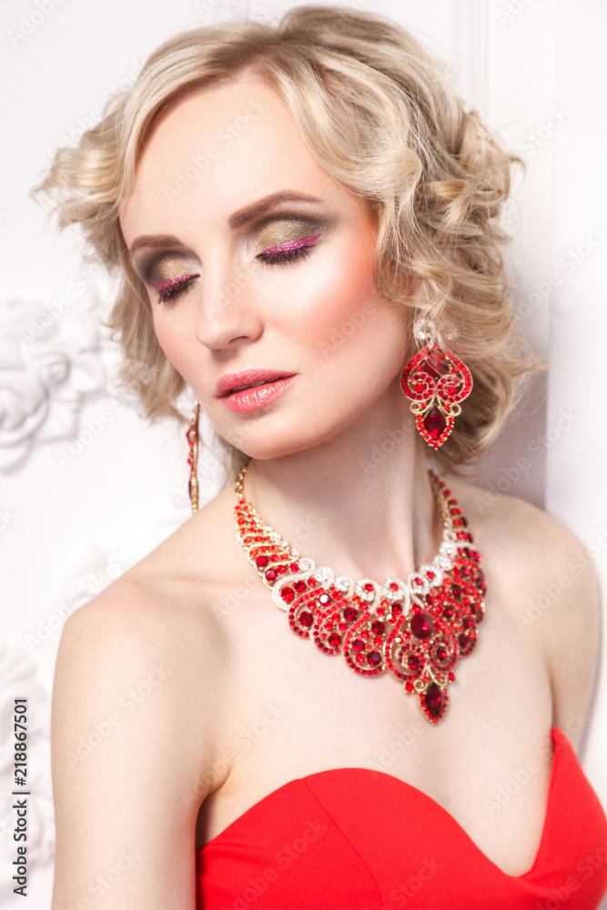 Closed eyes. Young blonde model with curly hairstile and beautiful makeup and elegant gewelry, indoor, Studio shot