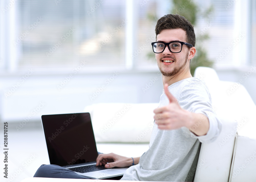 modern young sitting in front of the open laptop and showing thumb up