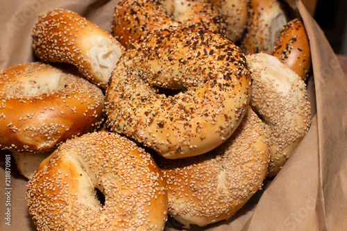 Variety of assorted authentic New York style Bagels with seeds in a brown paper bag.