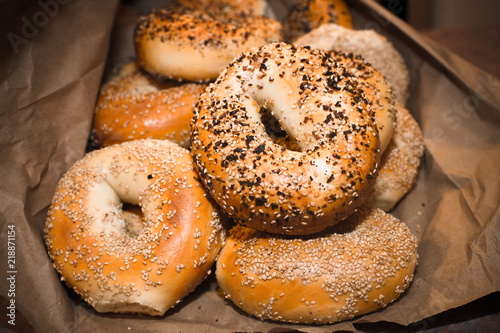 Variety of assorted authentic New York style Bagels with seeds in a brown paper bag.
