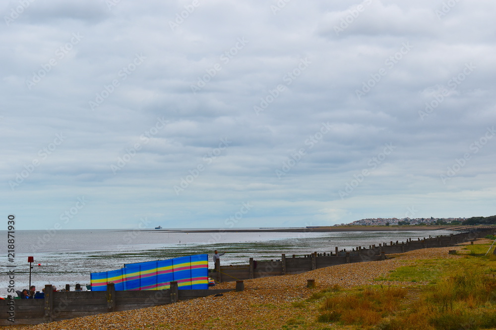 View of colourful windbreak on the sandy Herne Bay beach. Herne Bay, Kent, UK, August, 2018
