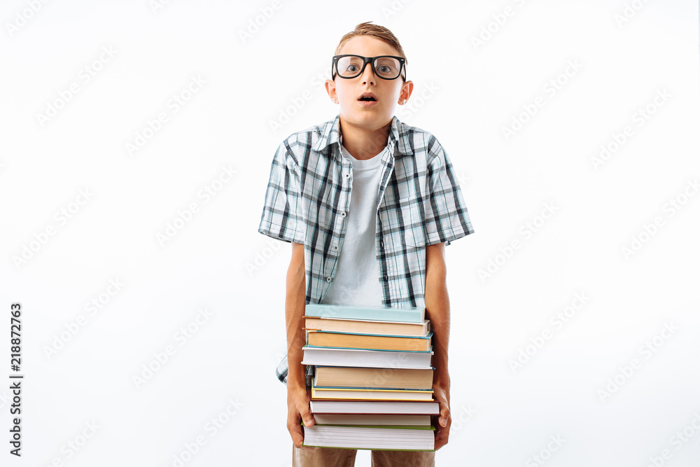 Beautiful student holding a stack of books, botany glasses hard to keep a large stack of books in the Studio on a white background