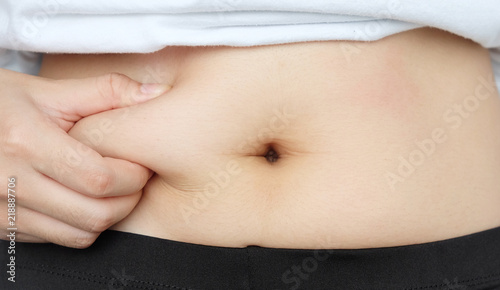 Side of woman hand catching fat body belly paunch , diabetic risk factor .