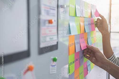 Web designer brainstorming for a strategy plan. Colorful sticky notes with things to do on office board. User experience (UX) concept. photo