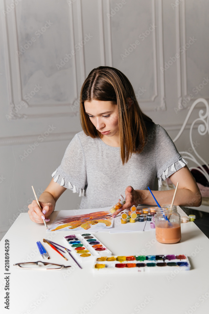 Fototapeta premium Pretty smiling young woman drawing a picture
