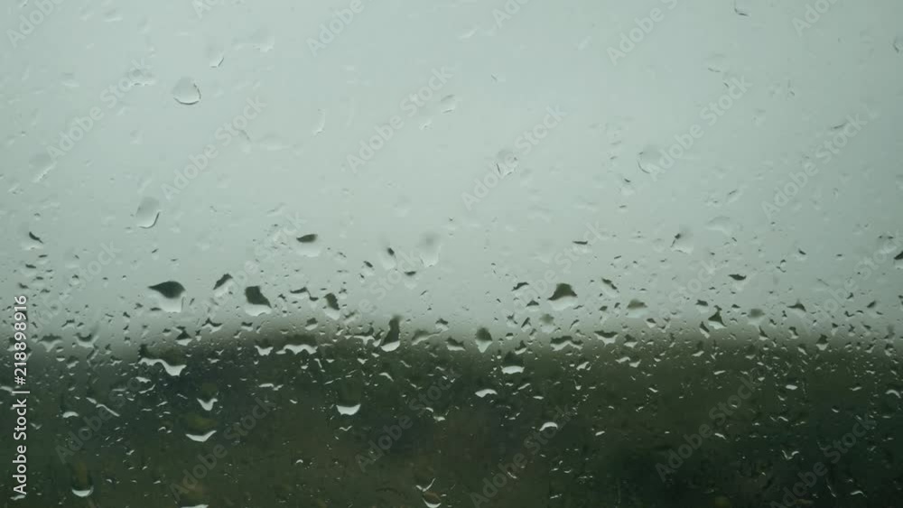 Rain drops appearing on a window glass, rain starting, droplets background Rain drops appearing on a window glass, rain starting, droplets background