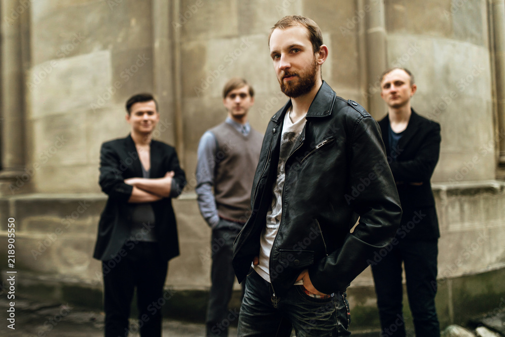 stylish handsome group of men standing and posing on the background of city street stylish handsome group of men standing and posing on the background of city street