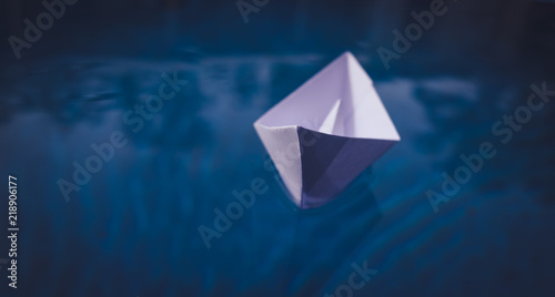 Childhood memory concept  paper origami boat on voyage in blue water