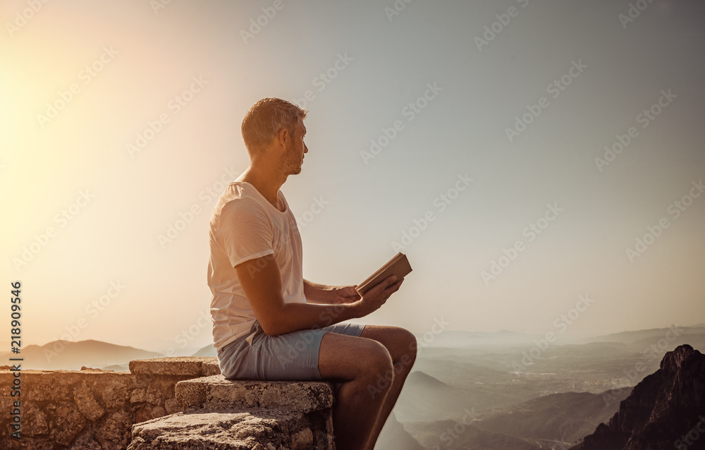 sitting book reading man over the mountains on sunset