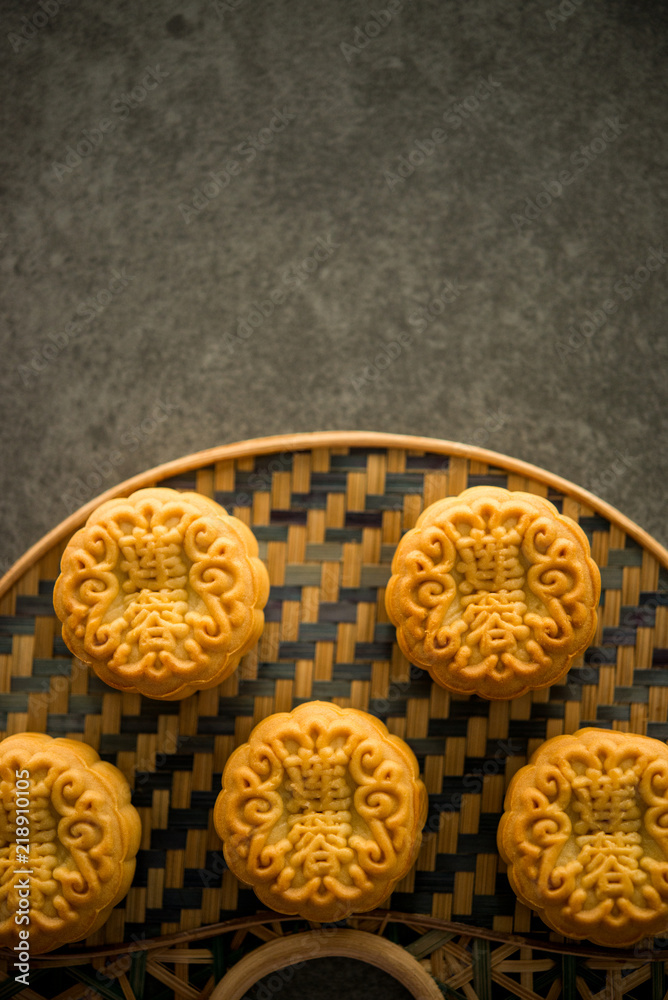 Moon cakes on bamboo background dark light with copyspace Moon cakes on bamboo background dark light with copyspace