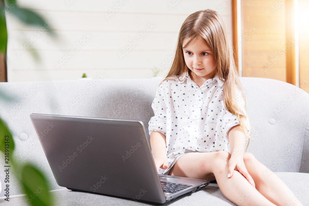 Pretty little brunette girl sitting on the sofa and using laptop Pretty little brunette girl sitting on the sofa and using laptop