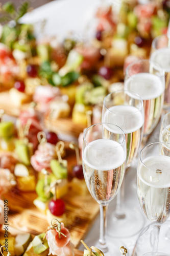 solemn happy new year banquet. Lot of glasses champagne or wine on the table in restaurant. buffet table with lots of delicious snacks. canapes, bruschetta, and little desserts on wooden plate board