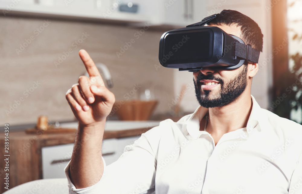 Handsome bearded man using virtual reality goggles in the modern flat Handsome bearded man using virtual reality goggles in the modern flat