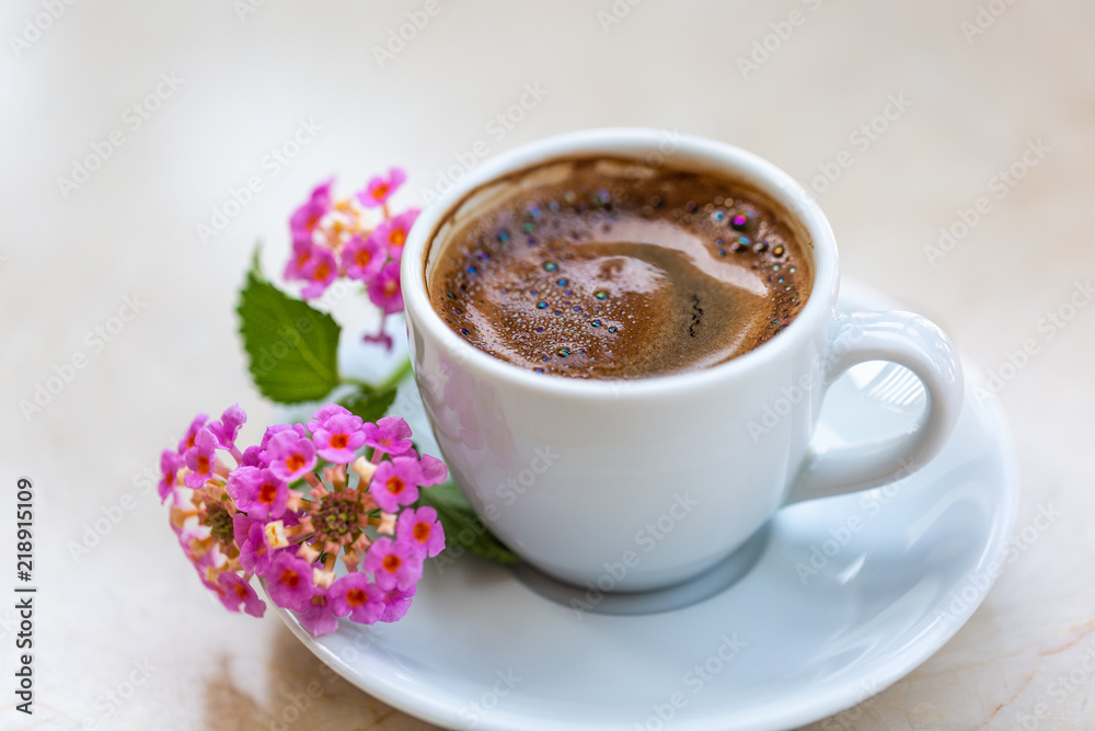 Traditional invigorating Turkish coffee. A white cup of coffee is decorated with flowers. Beautiful feed Traditional invigorating Turkish coffee. A white cup of coffee is decorated with flowers. Beautiful feed