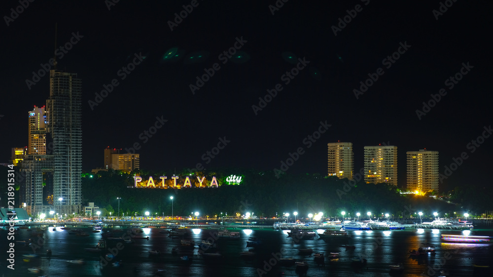 Pattaya sign at Pattaya beach bay with many boats floating in the sea night shot
