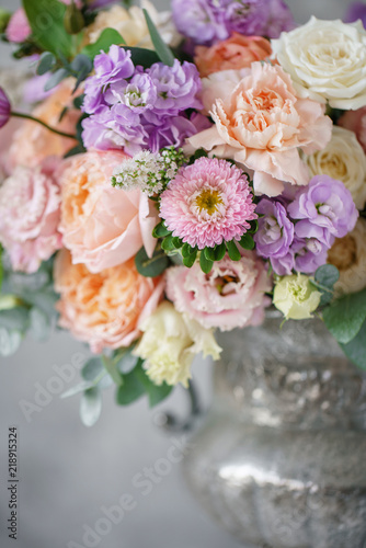 Gorgeous bouquet of different flowers. floral arrangement in vintage metal vase. table setting. lilac and peach color