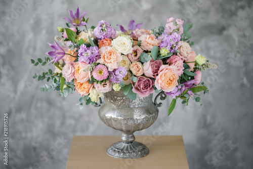 Gorgeous bouquet of different flowers. floral arrangement in vintage metal vase. table setting. lilac and peach color