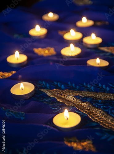 Flame candle lamps for the evening prayers. Diwali lighting on blue sari with golden embroidery