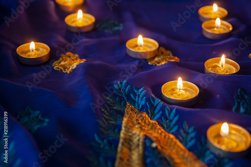 Flame candle lamps for the evening prayers. Diwali lighting on blue sari with golden embroidery
