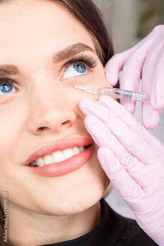 injection cosmetology. Caring for the skin around the eyes. Happy smiling relaxed eyes patient girl. Professional cosmetology. Beauty skin care. Trust your doctor