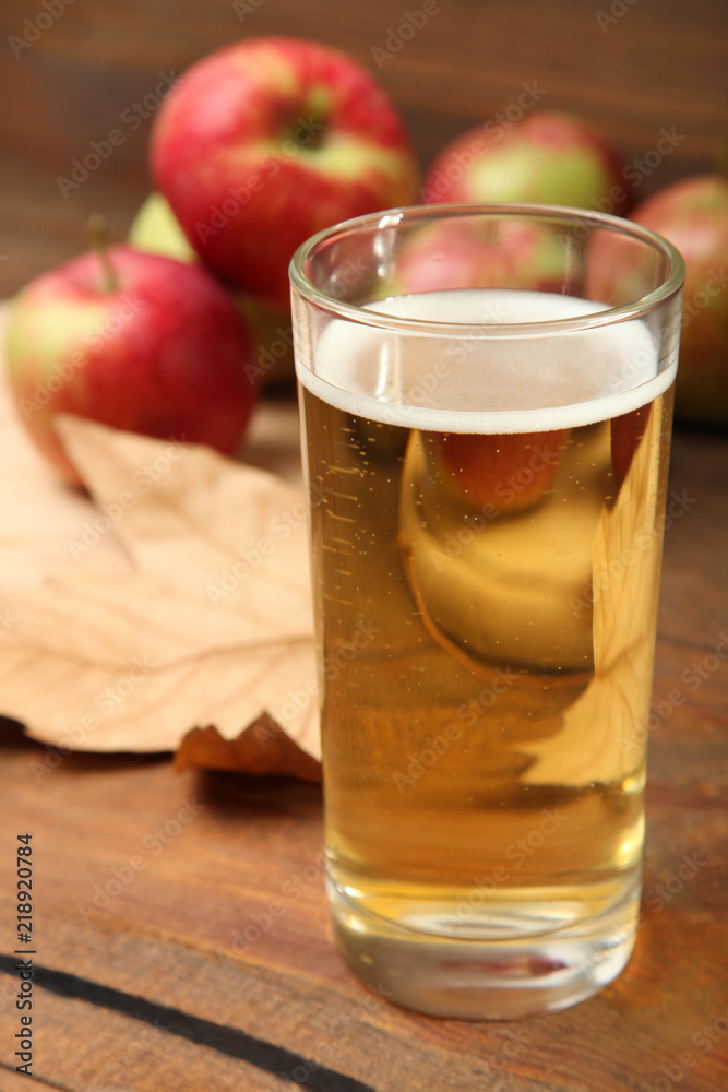 Apple cider in a glass on a brown wooden background. Apple cider in a glass on a brown wooden background.